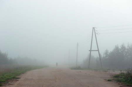 An empty road disappearing into the dense morning fog.の写真素材
