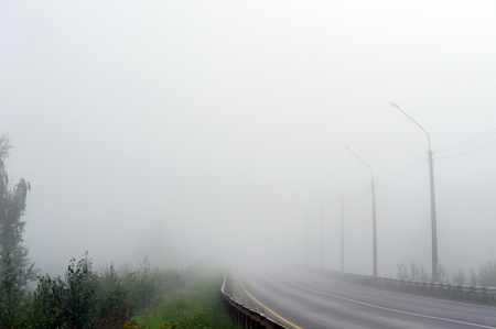 An empty road disappearing into the dense morning fog.の写真素材