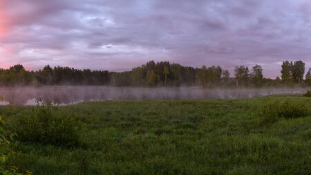Dawn on the shore of the lake with rising fog.の写真素材
