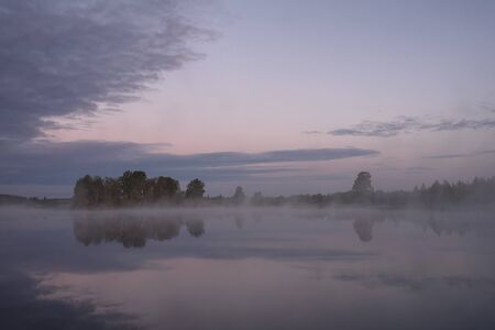 Dawn on the shore of the lake with rising fog.の写真素材