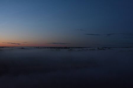 Midnight fog covers the fields and the river and the power lines.の写真素材