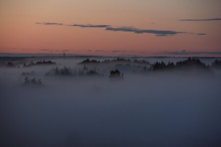 Midnight fog covers the fields and the river and the power lines.の写真素材