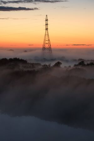 Midnight fog covers the fields and the river and the power lines.の写真素材