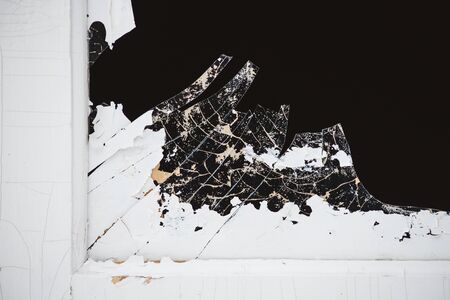 A broken window pane in the doorway, with sharp, dangerous edges of splinters and peeling paint.