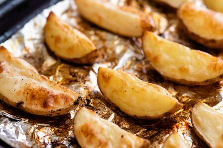 Slices of potatoes baked on foil in the oven until golden brown.の写真素材