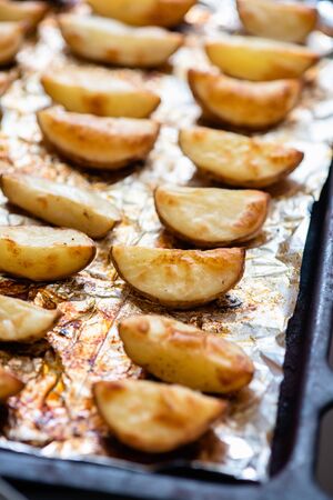 Slices of potatoes baked on foil in the oven until golden brown.の写真素材