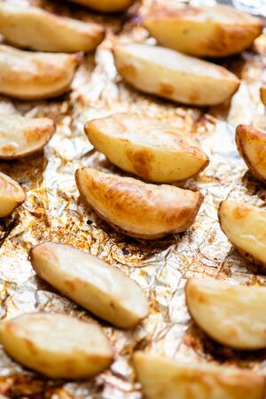 Slices of potatoes baked on foil in the oven until golden brown.の写真素材