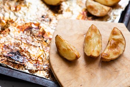 Slices of potatoes baked on foil in the oven until golden brown.の写真素材
