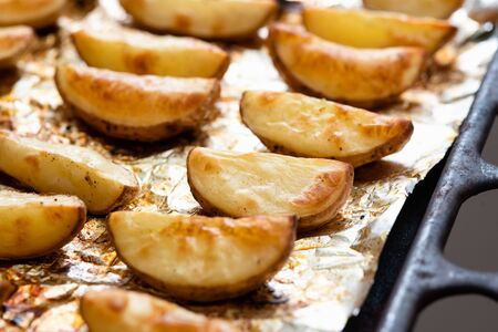 Slices of potatoes baked on foil in the oven until golden brown.の写真素材