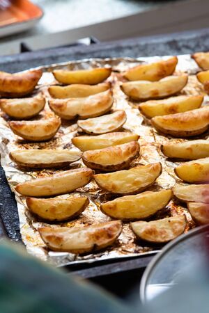 Slices of potatoes baked on foil in the oven until golden brown.の写真素材