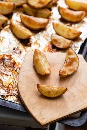 Slices of potatoes baked on foil in the oven until golden brown.の写真素材