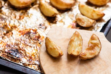 Slices of potatoes baked on foil in the oven until golden brown.の写真素材