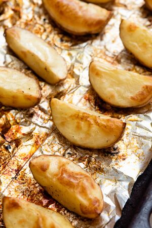 Slices of potatoes baked on foil in the oven until golden brown.の写真素材