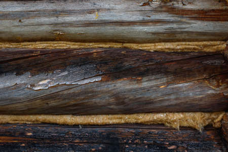 Aged, cracked and discolored logs of the building close up.の写真素材