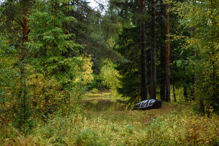 An old metal boat is made with your own hands on the shore of the lake in the autumn season.の写真素材
