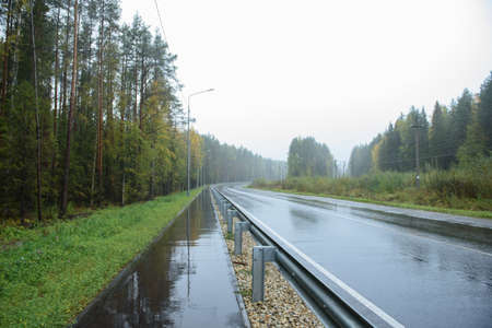 A road section with a pedestrian path located along it by rainy weatherの写真素材