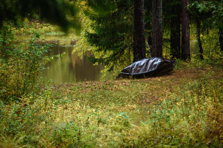 An old metal boat is made with your own hands on the shore of the lake in the autumn season.の写真素材