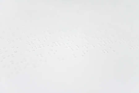 A fragment of text in Louis Braille printed on a standard sheet of paper using special printing equipment.の写真素材