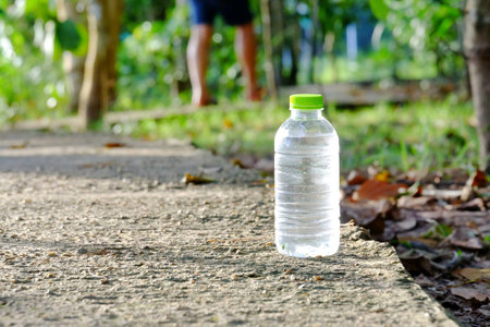 A plastic bottle of water on a cement walkway at the green park and sun lightの素材