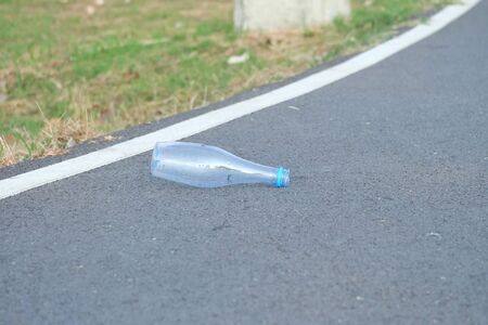 A plastic bottle of drinking water littering on the street ground floor at the green park green nature background for an environmental cleaning conceptの写真素材