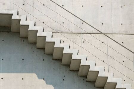 Cement stairs in outside the high modern building with handrails and sunlight shadowの写真素材