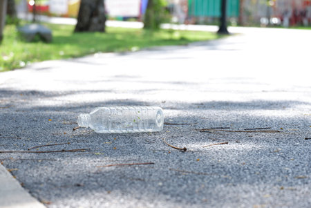 Littering plastic bottle with drinking water on the road at the green park for an environmental cleaning conceptの写真素材