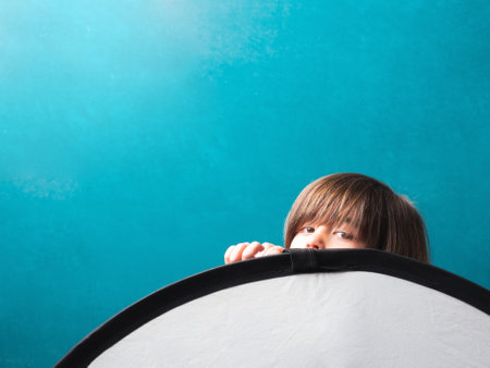 Child playing with the reflector during the photo session in front of the blackboard in a school...