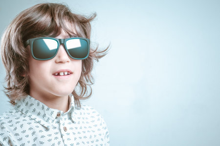 Boy in white shirt with blue details posing in a photo shoot with sunglasses.の写真素材
