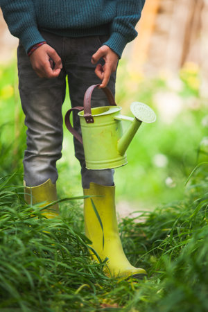Legs of a child wearing wellies and holding a watering can.の写真素材