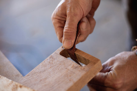 Capturing the skilled hands of a woodworker meticulously sanding and shaping the wood using...