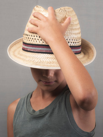 Boy wearing a straw hat. The hat covers part of his face, especially his eyes.の写真素材