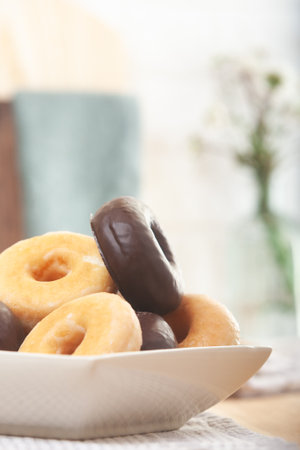 Lots of chocolate and sugar donuts filling the plate. Close-up. Out of focus background.の写真素材