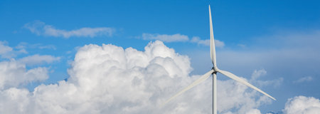 Panoramic view of the blades of a wind turbine over a blue sky with large clouds.の写真素材