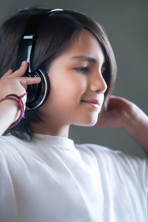 Portrait of a child listening to music with headphones. She is smiling and relaxed enjoying her...