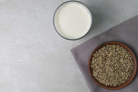 Homemade milk from hemp seeds. There is a glass of milk and clay bowl with hemp seeds on the concrete surface.の写真素材