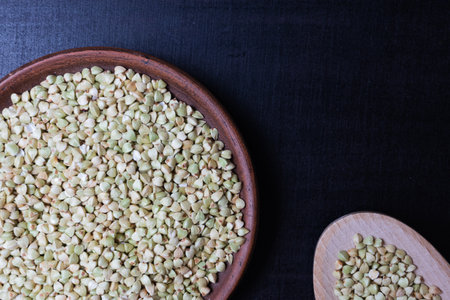 Green buckwheat in a clay cup on a black background. Food background.の写真素材