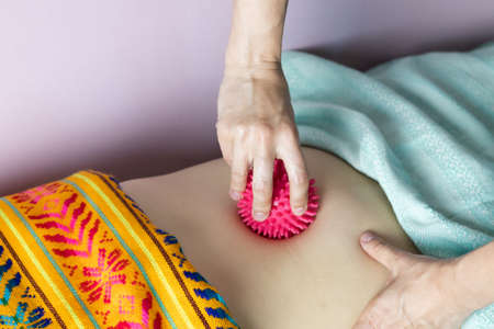 The postpartum doula uses a massage ball to massage the navel to lift the internal organs.の写真素材
