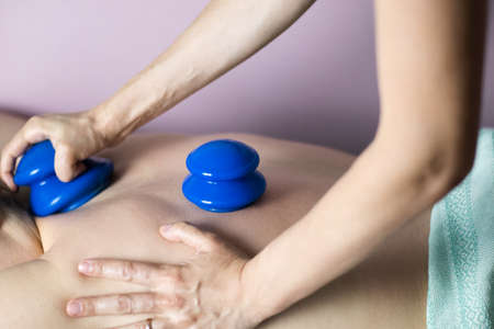A postpartum doula gives a woman a back massage with vacuum silicone cups.の写真素材