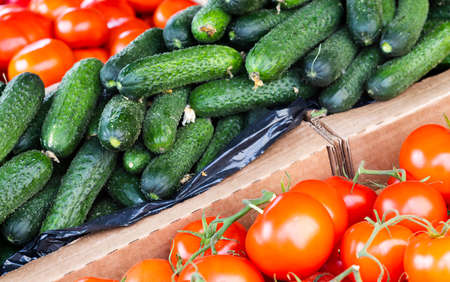 Ripe tomatoes and cucumbers on the counter in a grocery storeの写真素材