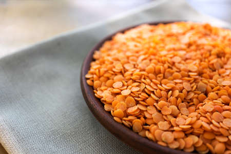 Red lentils in a clay plate on a wooden table.の写真素材