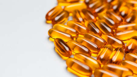 Yellow oval omega-3 capsules on a gray background on the right. Space for text.の写真素材