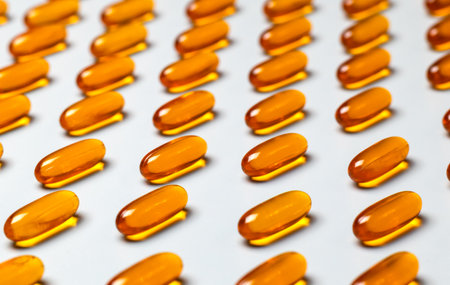 Yellow oval omega-3 capsules on a gray background.の写真素材