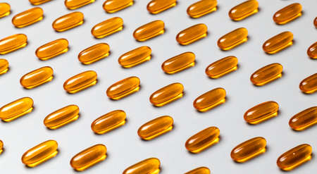 Yellow capsules omega-3 on a gray background. Pattern. Pantone colors of 2021.の写真素材