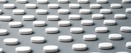 Patern of white calcium capsules with vitamin D on a gray background. Medical background.の写真素材