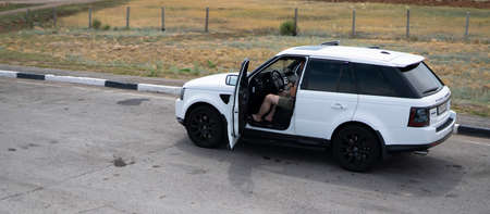 Kazakhstan, Nur-Sultan, July 2021 Range Rover Sport of white color stands at the roadside. The drivers door is open and a man is driving.のeditorial素材
