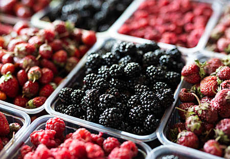 Blackberries, raspberries and strawberries on the counter of a vegetable shop.の写真素材