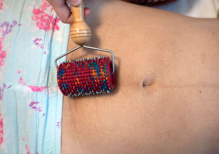 Postpartum doula shows how to massage a cesarean scar with a Lyapko applicator.の写真素材