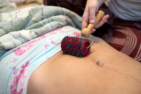 Postpartum doula shows how to massage a cesarean scar with a Lyapko applicator.の写真素材