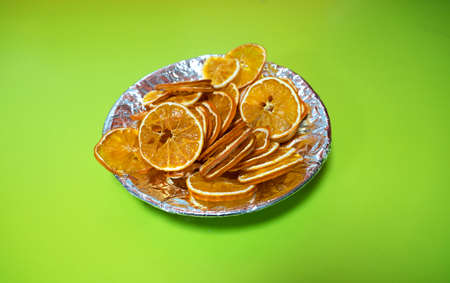 Dried oranges in a foil plate on a green background.の写真素材