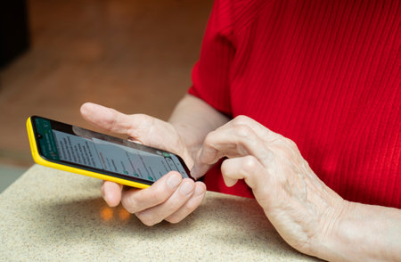 The phone is in the hands of an elderly woman of retirement age. Smartphone use by the elderly.の写真素材